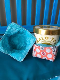 an empty cupcake tin sitting on top of a blue chair next to a container of ice cream