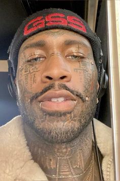 a man with tattoos on his face and headphones around his neck is looking at the camera