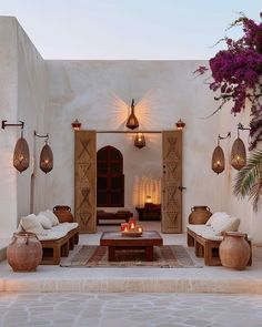 an outdoor living area with seating and potted plants on either side of the fire place