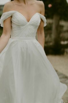 a woman in a white dress is walking down the street with her hand on her hip