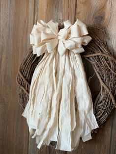 a wreath hanging on the side of a wooden door with a bow tied to it