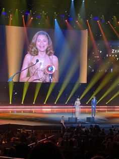 a woman standing on top of a stage next to a man in front of a screen