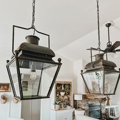 two lanterns hanging from the ceiling in a room with white walls and ceilings, along with a fireplace