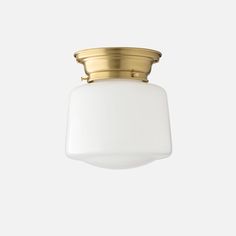 a light fixture with a white glass shade on it's side and gold trim