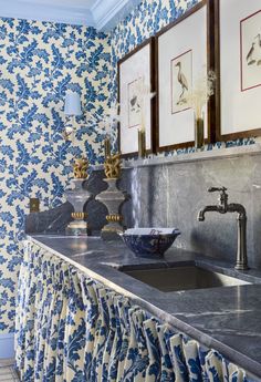 a bathroom with blue and white wallpaper, sink and framed pictures on the wall