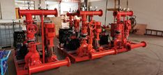 red pipes and valves are lined up in an industrial setting with other equipment on the floor