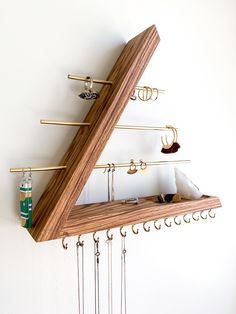 a triangle shaped shelf with hooks and jewelry hanging from it