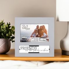 a photo frame sitting on top of a wooden table next to a potted plant