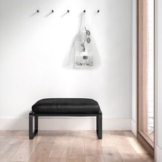 a black bench sitting in the middle of a room next to a wall with hooks on it