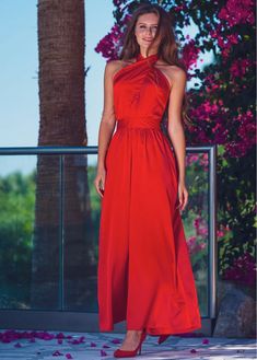 a woman in a red dress is standing outside