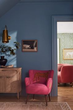 a living room with blue walls and pink chairs