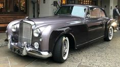 an old fashion car parked in front of a building