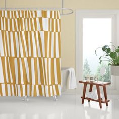 a yellow and white shower curtain next to a small table with a potted plant