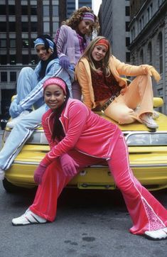 a group of people sitting on top of a yellow car in the middle of a street