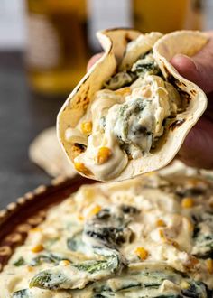 a hand holding a tortilla filled with cheese and vegetables