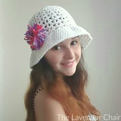 a woman wearing a white crochet hat with pink flowers on the brim