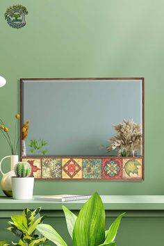 a mirror sitting on top of a green wall next to plants and potted plants