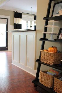 a shelf with baskets on top of it next to a door and a kitchen in the background