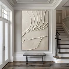 a large white painting hanging on the wall in a living room next to a stair case