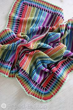 crocheted blanket made with multicolored yarns on top of a wooden bench