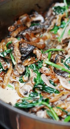 mushrooms and spinach cooking in a pan on the stove