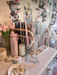 a table topped with lots of pink flowers next to a wall covered in pictures and candles