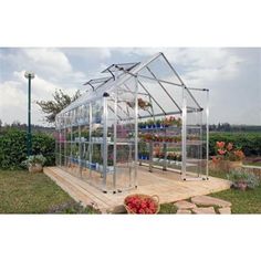 a small greenhouse in the middle of a field with lots of flowers inside and plants growing out of it