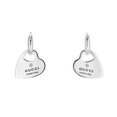 The Gucci Trademark line combines motifs and hexagonal charms with the name of the House. This pair of delicate hoop earrings feature a cut-out heart within the heart pendant. 925 sterling silver Heart with cut-out heart pendants Gucci Trademark engraving For pierced ears Length: 1 Inch Gucci Style#: YBD79630200100U Gucci Luxury Drop Earrings, Modern White Gold Jewelry With Logo Charm, Gucci Sterling Silver Jewelry With Heart Charm, Gucci Luxury Sterling Silver Earrings, Gucci White Gold Sterling Silver Earrings, Luxury Gucci Sterling Silver Earrings, Gucci Sterling Silver Earrings As Gift, Gucci Sterling Silver Earrings For Gift, Elegant Gucci Sterling Silver Earrings