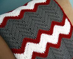 a crocheted blanket on the back of a woman's arm with a red and white design