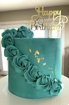 a birthday cake with blue frosting and gold icing flowers on the top is sitting on a table