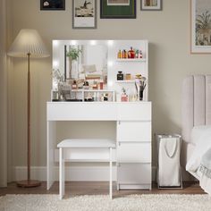 a white vanity with lights on it next to a bed and a lamp in a room