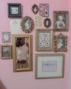 a pink wall with many framed pictures on it