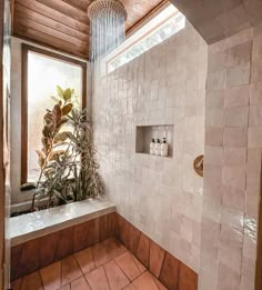 a bathroom with tiled walls and flooring next to a window, shower head and plants