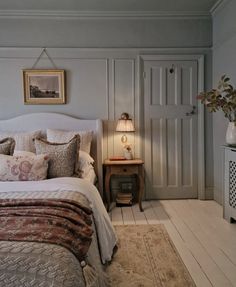 a bed sitting in a bedroom next to a dresser and lamp on top of a wooden floor