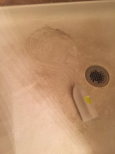 a dirty bathtub with a shower head in the middle and a sponge on the floor next to it