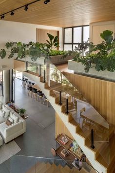 a living room filled with lots of furniture next to a stair case covered in plants