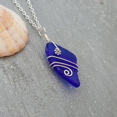 a blue sea glass pendant sitting on top of a table next to a seashell