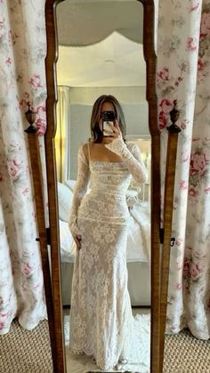 a woman taking a selfie in front of a mirror wearing a white lace dress