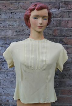 "Rayon blouse  Gorgeous lemon yellow Short-sleeved Mid-20th century -- 1950s or 1960s Intricate panel to front  Deep darts back and front  Shaping padding to shoulders  Cinched-in waist  Very good condition -- tiny hole at back (see photo) -- buttons replaced (see photo) Measurements All round at underarms -- 34\"/87cms Side seam -- 12\"/31cms Sleeve seam -- 1.5\"/4cms Length shoulder to hem -- 20\"/51cms" Fitted Retro Cream Top, Vintage Short Sleeve Blouse For Vintage Fashion, Vintage Cream Tops For Daywear, Retro Cream Blouse For Formal Occasions, Cream Retro Blouse For Formal Occasions, Fitted Yellow Vintage Blouse, Vintage Short Sleeve Formal Tops, Vintage Formal Short Sleeve Tops, Vintage Cream Short Sleeve Blouse