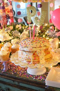 a table topped with lots of cupcakes and cake covered in sprinkles