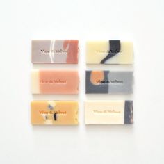 four bars of soap with different labels on them sitting next to each other in front of a white background