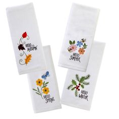 three white towels with embroidered flowers and words on them, one is saying hello spring