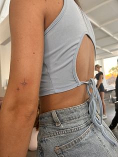 the back of a woman's shirt with a star tattoo on her left arm