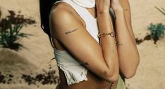 a woman with tattoos on her arms and chest posing for a photo in the desert