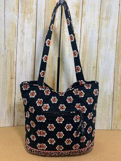 Pirouette Black pattern in a Bucket style small tote/purse with small multicolored floral designs This Bucket style tote bag is the perfect everyday purse.  Features include magnetic snap top closure, double straps, and a front zipper pocket with Vera Bradley ribbon pull.  Inside are 3 slip pockets and a zipper pocket with Vera Bradley ribbon pull tie, and Vera Bradley label.  The bottom section is reinforced to give the purse additional structure and the lining pockets and bottom lining fabric Multicolor Floral Print Shoulder Bag For Daily Use, Daily Use Multicolor Floral Print Shoulder Bag, Red Floral Print Shoulder Bag For Everyday Use, Black Rectangular Shoulder Bag With Floral Print, Small Shoulder Bag For Daily Use, Everyday Black Bag With Floral Print, Black Floral Print Tote Bag, Multicolor Floral Print Rectangular Shoulder Bag, Black Floral Print Shoulder Bag For Everyday Use