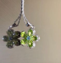 DeKara Designs Silver Metal- Sterling Silver, .925. Stones- 5 Natural Pear Shape Peridot 5 Carats, 1 Round Natural Blue Topaz, 5 Diamonds G-H Color SI2 Clarity 0.02 Carats. Measurements- Necklace is 18 Inches Long. Pendant is Bit Over An Inch Long Including Bail. Beautifully handmade Art Deco inspired halo diamond blue topaz peridot necklace made in sterling silver. There are five natural beautiful green pear shape peridot stones that are all professionally prong set. There is a prong set round Fine Jewelry Lime Green Birthstone, Fine Jewelry Lime Green Gemstone, Fine Jewelry In Green Peridot, Green Peridot Fine Jewelry, Fine Green Peridot Jewelry, White Gold Peridot Jewelry With Birthstone, Peridot Jewelry With Gemstone Accents For May Birthstone, Peridot Gemstone Jewelry For May Birthstone, White Gold Peridot Jewelry For May Birthstone