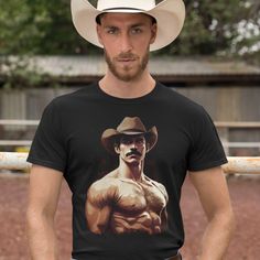 Unleash your inner cowboy with this eye-catching graphic tee, designed for confident, stylish individuals who love to make a statement. Our black, short-sleeved t-shirt features a striking illustration of a shirtless, muscular cowboy with a mustache and a hat, ready to turn heads wherever you go. Made from soft, high-quality fabric, it guarantees comfort and durability. Embrace your wild side and make this Rugged Cowboy Fantasy Tee a staple in your wardrobe today! Highlights: Eye-catching graphi Fitted Graphic Print T-shirt For Rodeo, Graphic Print T-shirt For Rodeo, Black Short Sleeve Western Tops, Black Western Style T-shirt For Rodeo, Western Style Short-sleeved Screen Print T-shirt, Black Western Crew Neck Top, Black Western Top With Graphic Print, Black Short Sleeve Western Style Top, Short Sleeve Graphic T-shirt For Rodeo