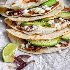 several tortillas are stacked on top of each other and topped with meat, cheese, and avocado