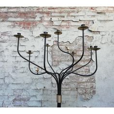 a metal candelabra with five candles on it in front of a brick wall