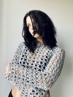 a woman with black hair wearing a crochet top